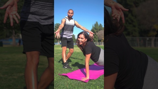 'A Man Goofing Beside A Woman Exercising Over A Yoga Mat'